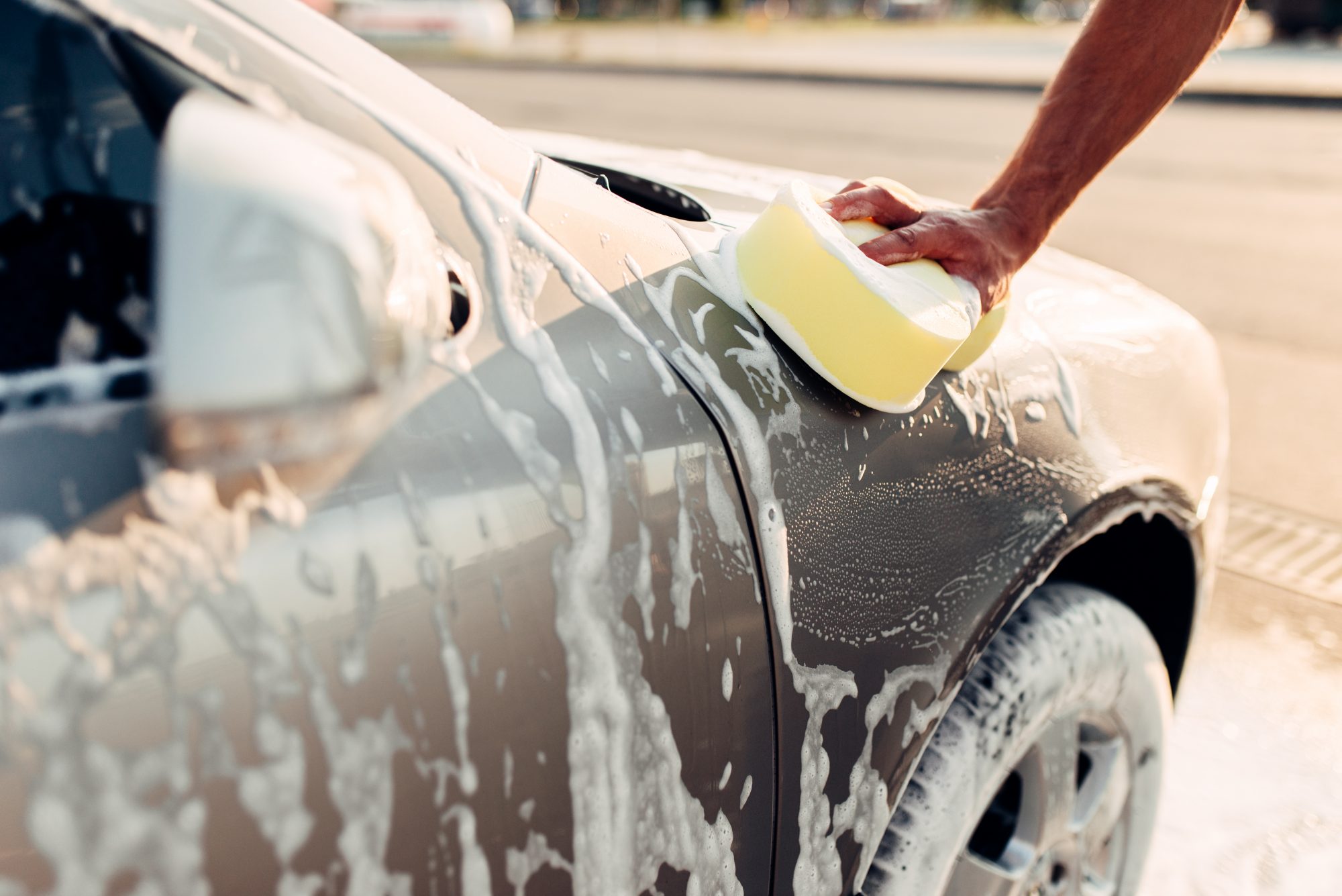 Male Hand Rubbing the Car with Soapy Foam